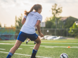 Niña jugando futbol en campo